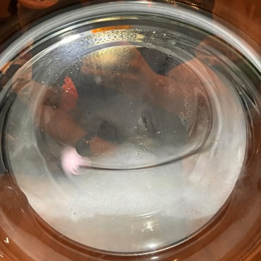 LG washer drum mid-cycle with water and suds visible through the glass door