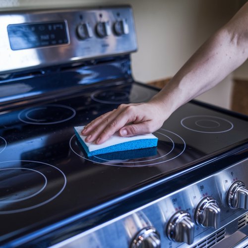 Easy home cleaning: image of person cleaning electric stovetop with sponge. Step-by-step cleaning guide